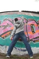 A young guy in a gray hoodie paints graffiti in pink and green c photo