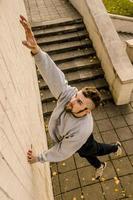 A young guy overcomes obstacles, climbing on concrete walls. The athlete practices parkour, training in street conditions. The concept of sports subcultures among youth photo