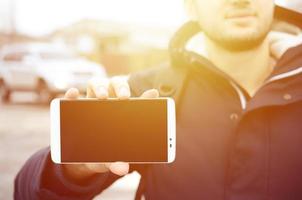 un joven demuestra una pantalla de teléfono inteligente en el fondo foto