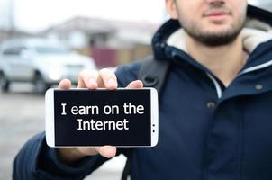 A young guy shows an inscription on the smartphone's display on photo