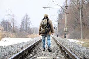 A man with a large backpack goes ahead on the railway track duri photo