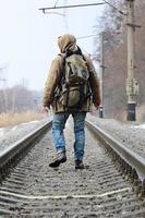 A man with a large backpack goes ahead on the railway track duri photo