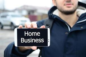 A young guy shows an inscription on the smartphone's display on photo