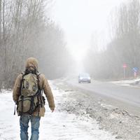 un hombre con una mochila grande camina por una carretera asfaltada suburbana foto