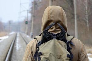 A man with a large backpack goes ahead on the railway track duri photo