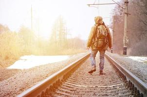 A man with a large backpack goes ahead on the railway track duri photo