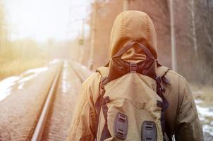 A man with a large backpack goes ahead on the railway track duri photo
