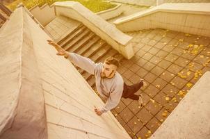 A young guy overcomes obstacles, climbing on concrete walls. The athlete practices parkour, training in street conditions. The concept of sports subcultures among youth photo