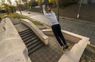 A young guy performs a jump through the space between the concrete parapets. The athlete practices parkour, training in street conditions. The concept of sports subcultures among youth photo