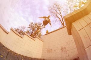 A young guy performs a jump through the space between the concrete parapets. The athlete practices parkour, training in street conditions. The concept of sports subcultures among youth photo