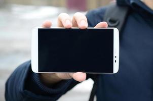 A young guy demonstrates a smartphone display on the background photo