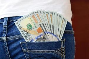 A large number of dollar bills lies in the back pocket of the girls jeans photo