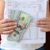 The girl holds in her hands the tax form and a large number of dollar bills photo