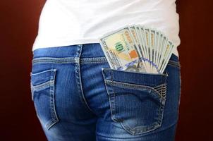 A large number of dollar bills lies in the back pocket of the girls jeans photo