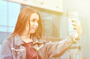 Young girl doing selfie on the background of an office building photo