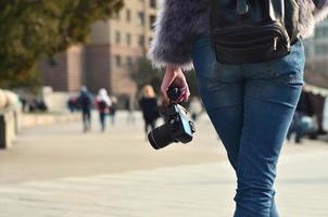 Rear view of a girl with a digital camera on a crowded street ba photo