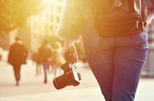 vista trasera de una chica con una cámara digital en una calle llena de gente ba foto