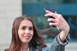 Young girl doing selfie on the background of an office building photo