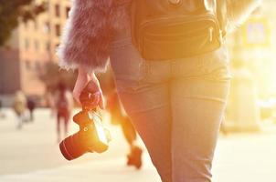 Rear view of a girl with a digital camera on a crowded street ba photo