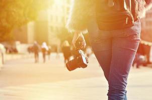 Rear view of a girl with a digital camera on a crowded street ba photo