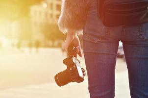 Rear view of a girl with a digital camera on a crowded street ba photo