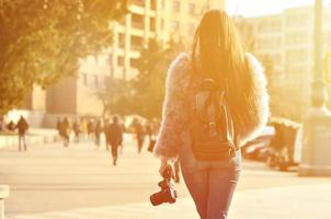 Rear view of a girl with a digital camera on a crowded street ba photo