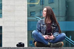 A girl photographer uses a smartphone and sits on a granite para photo