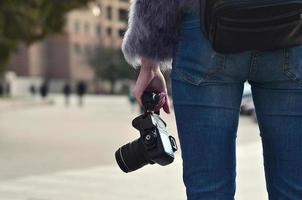 vista trasera de una chica con una cámara digital en una calle llena de gente ba foto