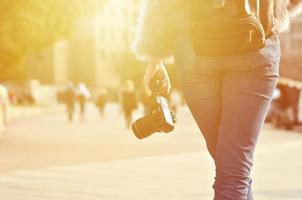 vista trasera de una chica con una cámara digital en una calle llena de gente ba foto