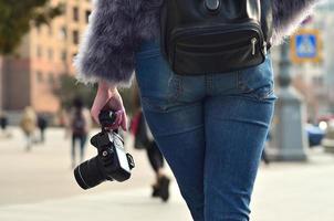 Rear view of a girl with a digital camera on a crowded street ba photo