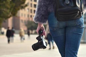 vista trasera de una chica con una cámara digital en una calle llena de gente ba foto