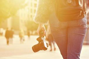 vista trasera de una chica con una cámara digital en una calle llena de gente ba foto