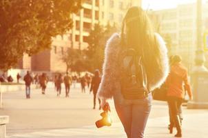 Rear view of a girl with a digital camera on a crowded street ba photo