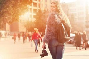 Rear view of a girl with a digital camera on a crowded street ba photo