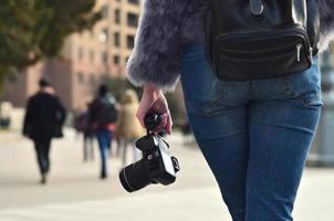 vista trasera de una chica con una cámara digital en una calle llena de gente ba foto