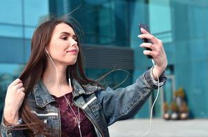 jovencita haciendo selfie en el fondo de un edificio de oficinas foto