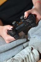 una niña juega videojuegos con un joystick negro con muchos b