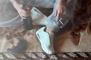 A girl sitting on the couch, smoking a cigarette, drinking beer photo