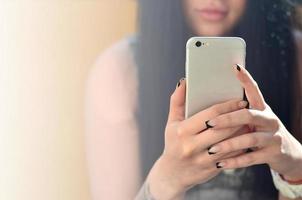 The brunette girl uses a modern touch smartphone photo
