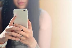 The brunette girl uses a modern touch smartphone photo