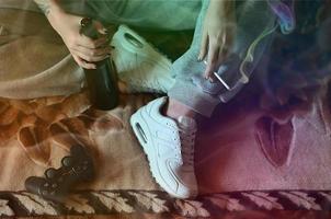 A girl sitting on the couch, smoking a cigarette, drinking beer photo