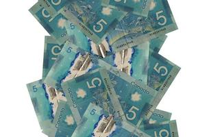 5 Canadian dollars bills flying down isolated on white. Many banknotes falling with white copyspace on left and right side photo