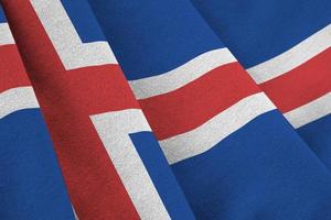 Iceland flag with big folds waving close up under the studio light indoors. The official symbols and colors in banner photo