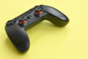 Modern black video game controller on yellow background. Video game speedrun concept or Esports competition challenge photo