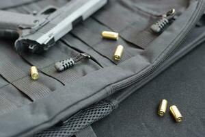 9mm bullets and pistol lie on a black tactical backpack photo