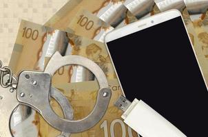 100 Canadian dollars bills and smartphone with police handcuffs. Concept of hackers phishing attacks, illegal scam or malware soft distribution photo