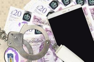 20 British pounds bills and smartphone with police handcuffs. Concept of hackers phishing attacks, illegal scam or malware soft distribution photo