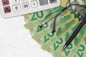 20 Canadian dollars bills fan and calculator with glasses and pen. Business loan or tax payment season concept photo