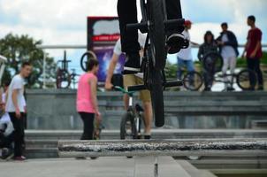 un ciclista salta sobre una tubería en una bicicleta bmx. mucha gente con bicicletas en el fondo. concepto de deportes extremos foto