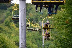 People ride on a cable car. The legs of passengers hang over the mountain forest photo